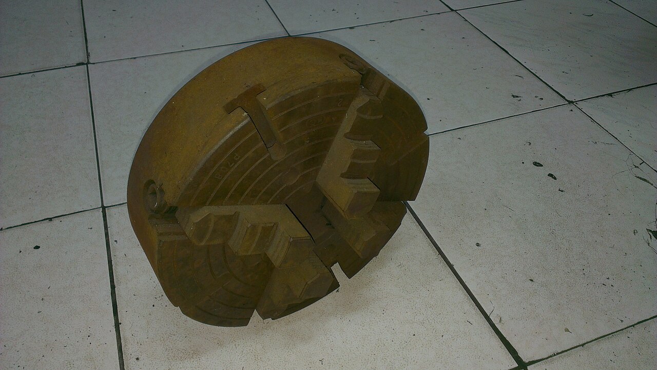 Figure 2 — A four-jaw independent chuck. Each jaw adjusts separately, so it holds non-round work and can be indicated to run dead true. Source: Wikimedia Commons.