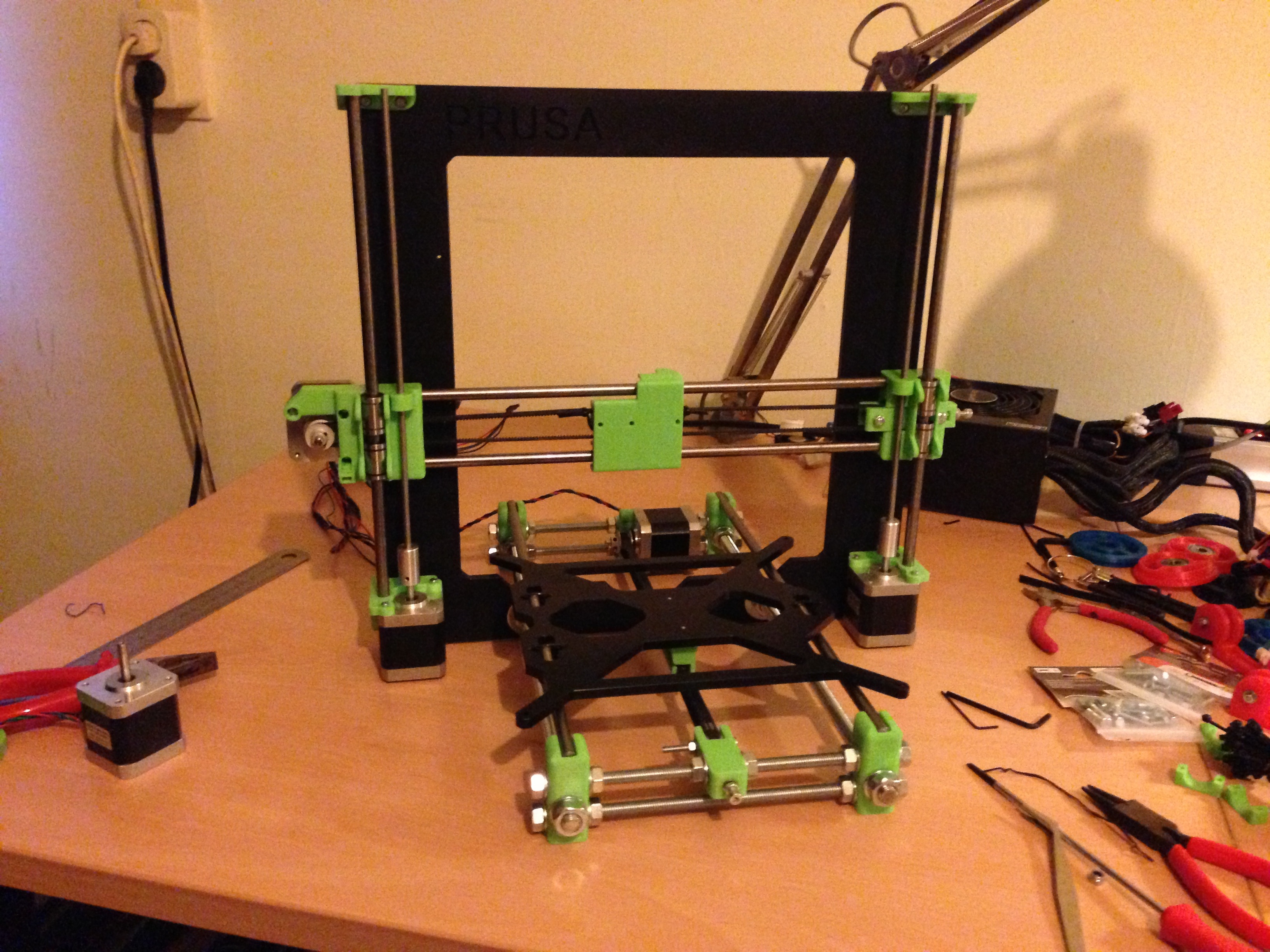 Figure 4 — A partially-built i3-style printer mid-assembly. The kit version of the MK3S+ is assembled by the owner over roughly a day from a famously good manual; the exercise leaves the builder kn…